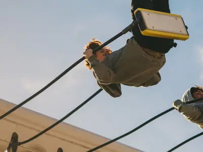 Two people swing high in the air on an amusement ride against a blue sky